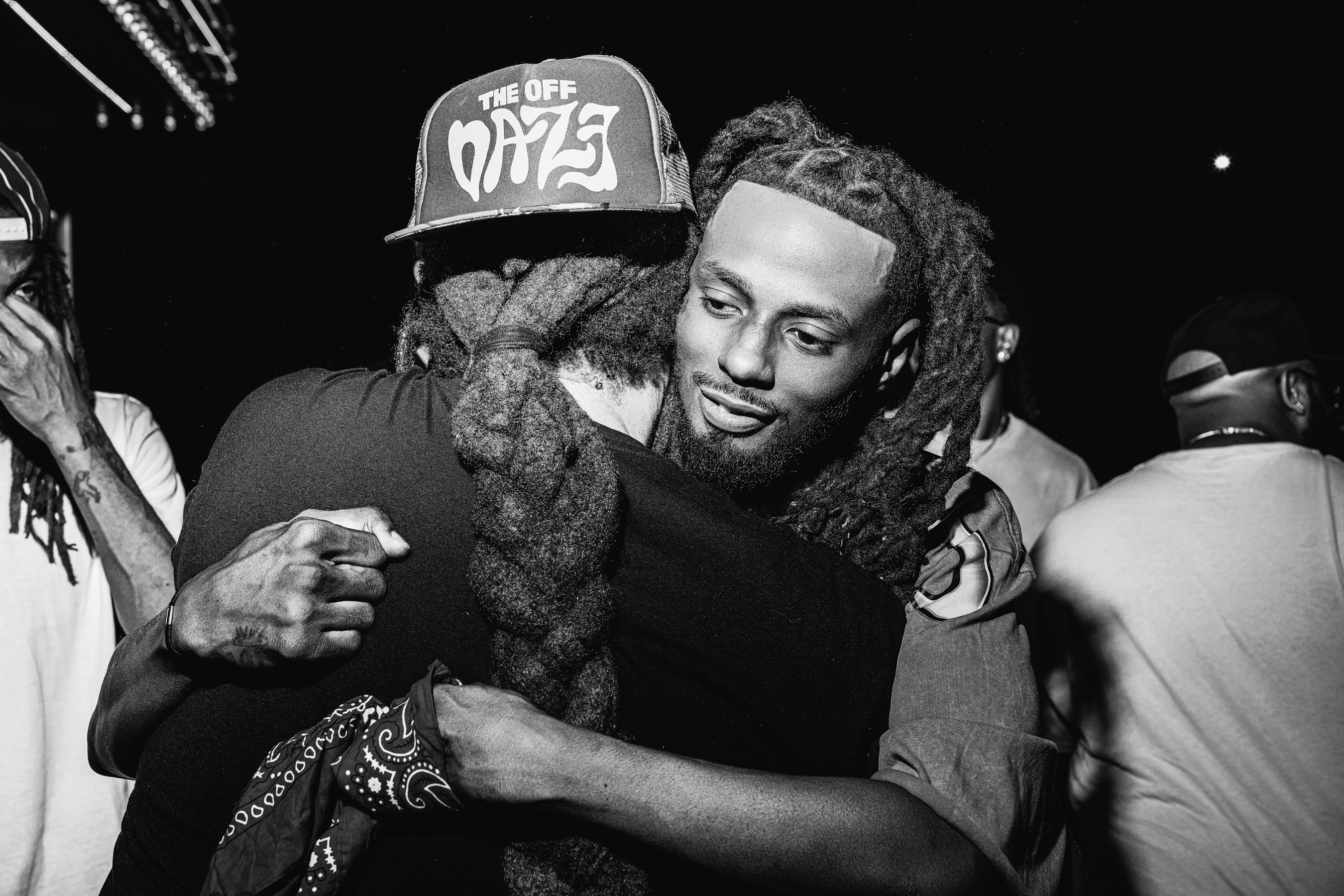 Two attendees embracing during the Lyric League Series launch, candid moment, night lighting